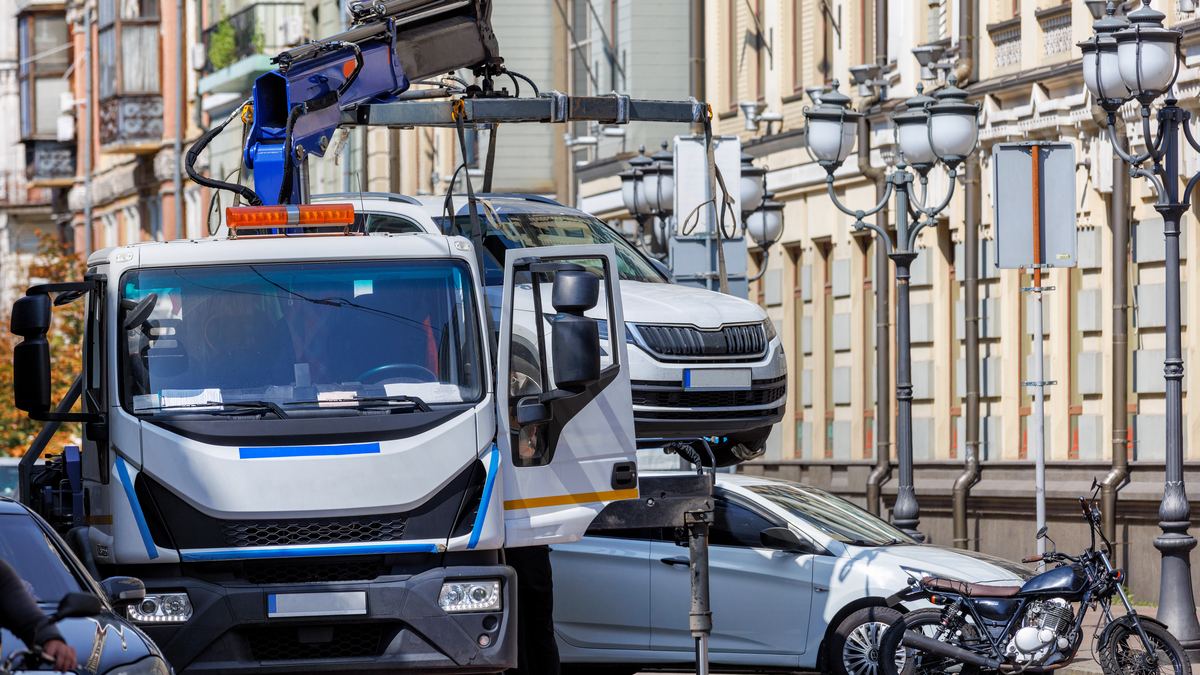 Auto, das in einer Straße in Sofia auf einen Abschleppwagen geladen wird, und ein Gemeindemitarbeiter mit Unterlagen.